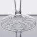 A close up of a clear Fineline Flairware plastic wine goblet with a curved rim.
