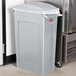 A Rubbermaid light grey plastic trash can with a lid.