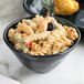 A bowl of pasta salad with olives and tomatoes in a green GET Cosmo melamine bowl.