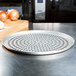 An American Metalcraft Super Perforated Pizza Pan on a counter with onions.