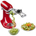A white KitchenAid stand mixer with spiralizer attachment spiralizing cucumbers into a bowl of salad.