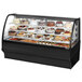 A True black refrigerated bakery display case with various cakes behind curved glass.