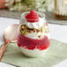 A Visions stemless plastic wine glass filled with a dessert topped with a raspberry and whipped cream.
