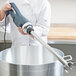 A person using an AvaMix heavy-duty blending shaft to mix a large pot in a professional kitchen.