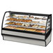 A True curved glass dry bakery display case filled with various pastries.