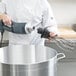 A person using an AvaMix whisk to mix a large pot.