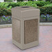 A Commercial Zone StoneTec rectangular trash can with square base and riverstone panels on a brick surface.