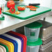 A green Rubbermaid cutting board on a kitchen counter with several different colored plastic containers.