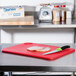 A Rubbermaid red cutting board with meat and a knife.
