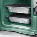 A granite green Cambro front loading food pan carrier with food trays inside.