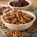 A Carlisle tan melamine nappie bowl filled with pretzels and nuts.