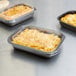 Clear PET lids on three small rectangle containers of macaroni and cheese.
