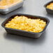 A tray of macaroni and cheese in a Solut Bake and Show paperboard tray on a table.