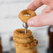 A hand uses a Clipper Mill stainless steel tower to stack fried onion rings.