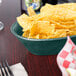 A table with a bowl of jalapeno chips served in an oval polyethylene basket.