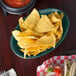 A plate of chips and salsa in HS Inc. jalapeno oval baskets on a table in a Mexican restaurant.