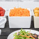 A Tablecraft white square bowl with salad and shredded carrots.