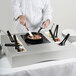 A chef using a Tablecraft countertop induction station to cook food in a pan.