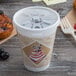 A Dart foam coffee cup with a translucent lid and straw slot next to a pastry.