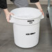 A woman holding a white Rubbermaid Brute ice bucket full of ice.