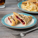 A GET Kanello Diamond Ivory melamine plate with pastries and a sandwich on it.