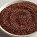 A bowl of brown organic red quinoa on a table.