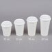 A row of white Choice paper cups with white hinged travel lids.