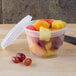 A Pactiv translucent plastic deli container filled with fruit and topped with a plastic lid.