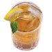 A glass of ice tea with a lemon slice and mint on the rim next to a Manitowoc half size cube ice machine.