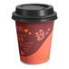 A white paper coffee cup with a red and orange coffee logo and a black lid.
