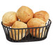 A black Clipper Mill by GET iron powder coated short oval tuscan basket filled with bread rolls.