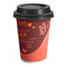 A white paper coffee cup with a red and orange coffee print and black lid.