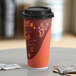 A close-up of a Choice Coffee Print Poly Paper Hot Cup with a lid on it.