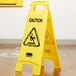 A yellow Rubbermaid double sided caution wet floor sign.