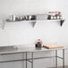 A Regency stainless steel wall shelf above a stainless steel counter with food items on it.
