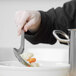 A person using a Vollrath perforated stainless steel basting spoon to serve vegetables.