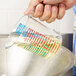A hand pouring liquid into a Rubbermaid clear polycarbonate plastic measuring cup.