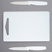 A white rectangular Choice cutting board with two knives on it.