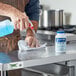 A man using Edwards-Councilor Steramine Sanitizing Tablets to clean a counter in a professional kitchen.