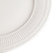 A close up of a 9 3/8" ivory china plate with an embossed rim.