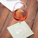 A Carlisle white plastic wine glass filled with wine on a table with a napkin.