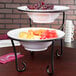 An American Metalcraft Ironworks two-tier display stand holding bowls of fruit.