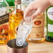 A hand using a Choice clear plastic utility scoop to add ice to a drink.