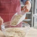 A person using a Choice clear plastic utility scoop to pour oats into a bowl.