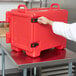 A person opening a red container with a Cambro Ultra Pan Carrier logo on it.