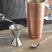 A close-up of an American Metalcraft stainless steel jigger on a table.