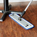 3M blue wet mop pad cleaning a wooden floor.