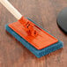A 3M Doodlebug orange pad holder on a wood surface.