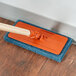 A 3M Doodlebug blue scrubbing pad on a wooden floor.