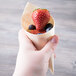 A hand holding a Tablecraft wooden cone filled with strawberries and blueberries.